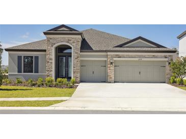 Charming single-story home with stone accents, a well-manicured lawn, and an attached two-car garage at 12977 Long Valley Cir, Spring Hill, FL 34609