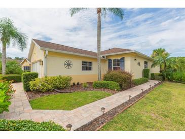 Exterior view of a yellow house with a landscaped yard at 1908 Sterling Glen Ct, Sun City Center, FL 33573