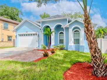 Charming home featuring a light blue exterior with a brick driveway and an attached two-car garage at 803 W Sligh Ave, Tampa, FL 33604