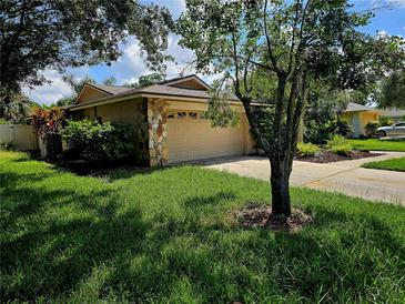 Single-story home with attached garage and landscaped yard at 3582 Fairway Forest Dr, Palm Harbor, FL 34685