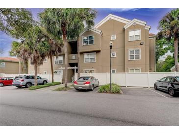 Tan colored building exterior with palm trees and parking at 15215 Amberly Dr # 206, Tampa, FL 33647