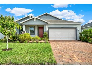 One-story home with gray siding, red door, and brick paver driveway at 14424 59Th E Cir, Bradenton, FL 34211