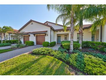 Charming villa showcasing a well-maintained lawn, tropical landscaping, and a private two-car garage at 16850 Whisper Elm St, Wimauma, FL 33598