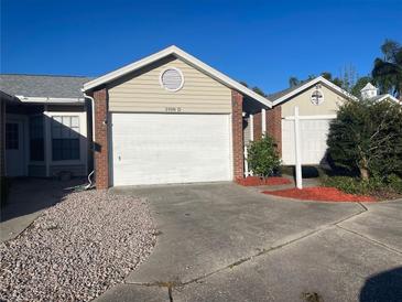 Tan house with white garage door, red mulch, and small landscaping at 3198 Claremont Pl # D, Palm Harbor, FL 34683