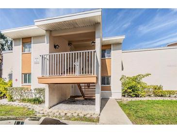 Two-story condo building features a private covered balcony, walkway, and manicured landscaping at 621 99Th N Ave # 102, St Petersburg, FL 33702