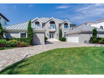 Two-story house with gray metal roof, white garage door, and landscaped yard at 2509 N Dundee St, Tampa, FL 33629