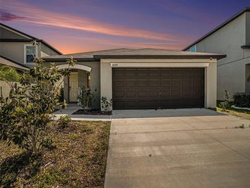 Charming house with a brown garage door and landscaping at 16762 Delia St, Wimauma, FL 33598
