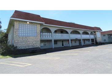 Exterior view of a light-colored building with a red roof, balconies, and ample parking at 6026 22Nd N Ave # 5, St Petersburg, FL 33710