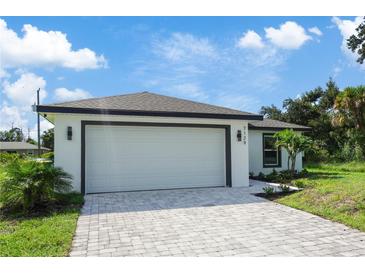 Modern house exterior featuring a white exterior, gray paver driveway and a two-car garage at 21279 Leonard Ave, Port Charlotte, FL 33954