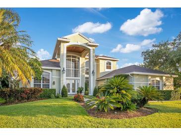 Beautiful two-story home with manicured lawn, large windows, and a grand arched entryway, creating an inviting facade at 1935 Lago Vista Blvd, Palm Harbor, FL 34685