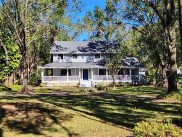 Two-story house with wraparound porch, and a spacious lawn at 5455 Lake Le Clare Rd, Lutz, FL 33558