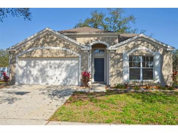 Charming single-story home featuring a two-car garage, neutral stucco exterior, and well-maintained landscaping at 26933 Carmen Pl, Lutz, FL 33559