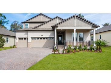 Inviting two-story home featuring a three-car garage, covered porch, and beautifully landscaped front yard at 4656 Southern Valley Loop, Brooksville, FL 34601