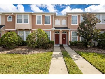 Two story townhome with red door and landscaped lawn at 6950 Towering Spruce Dr, Riverview, FL 33578