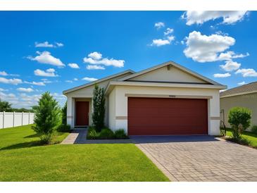Charming single-story home with a well-maintained lawn, paver driveway, and a lovely red two-car garage door at 11883 Brighton Knoll Loop, Riverview, FL 33579