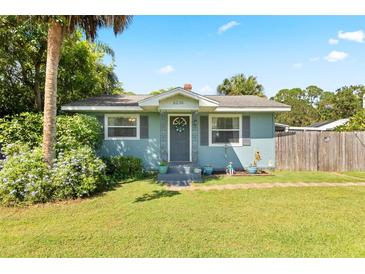 Light blue single story house with gray door, landscaping, and a well-maintained lawn at 6030 62Nd N St, St Petersburg, FL 33709
