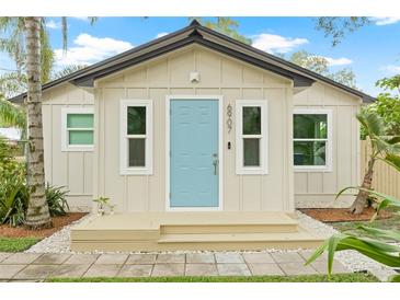 Charming cottage-style home featuring a light blue front door and neutral siding at 6907 N 20Th St, Tampa, FL 33610