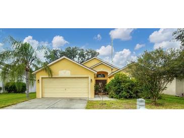 Cute yellow house with a two-car garage and well-manicured lawn at 1122 Vinetree Dr, Brandon, FL 33510