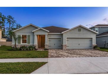 Charming single-story home featuring a spacious three-car garage and beautifully landscaped front yard at 23176 Pachino Way, Lutz, FL 33549