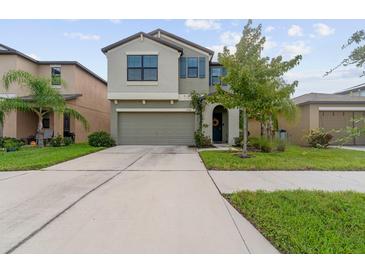 Two-story house with a green exterior, two-car garage, and landscaping at 15630 Greenleaf Bay St, Sun City Center, FL 33573