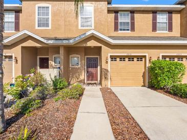 Inviting two-story townhome with a well-manicured lawn, charming facade, and attached garage at 12820 Belvedere Song Way, Riverview, FL 33578