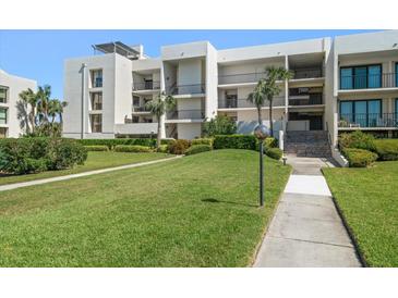 Exterior of condo building with lush landscaping and walkway at 50 Coe Rd # 322, Belleair, FL 33756