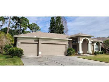 Tan two-car garage home with manicured lawn at 4467 Worthington Ct, Palm Harbor, FL 34685