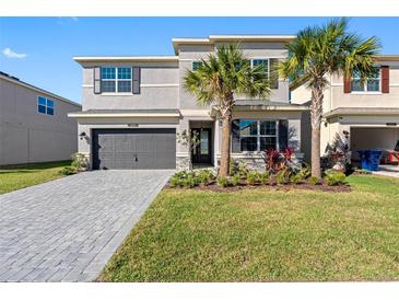 Beautiful two-story home boasting an attached garage, palm trees, and manicured front lawn at 32707 Tamarind Grove Ln, Wesley Chapel, FL 33543