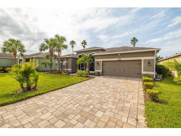 One-story home with a large paved driveway, landscaping, and a two-car garage at 10211 Cleghorn Dr, San Antonio, FL 33576