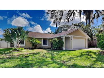 Tan one-story house with a two-car garage and lush lawn at 6969 Oldgate Cir, New Port Richey, FL 34655