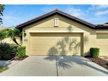 Attached garage with tan door and landscaping at 5648 Sunset Falls Dr, Apollo Beach, FL 33572