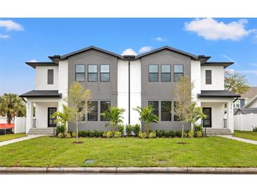 Modern townhomes featuring manicured lawns, gray and white facades, and black framed windows at 2709 W North B St # 2, Tampa, FL 33609