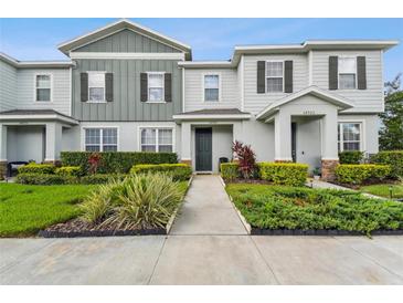Charming townhome featuring a manicured lawn with lush landscaping, a walkway, and pleasant curb appeal at 14929 Promenade Pkwy, Odessa, FL 33556