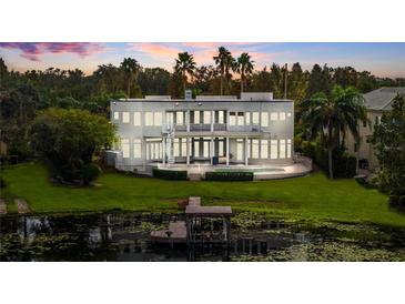Modern two-story home featuring a backyard pool, lake, and dock with sunset views at 2905 Safe Harbor Dr, Tampa, FL 33618