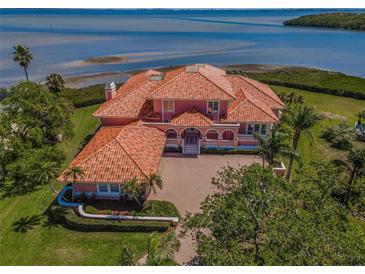 Stunning waterfront property with a clay tile roof, lush landscaping, and a spacious driveway at 3418 Braeside Pl, Clearwater, FL 33759