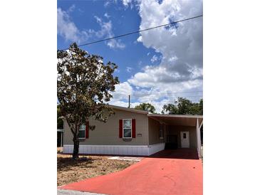 Charming single-story home with a red driveway and beautiful landscaping with a tree in the front yard at 36822 Kay Ave, Zephyrhills, FL 33542