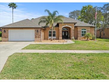 Single-story home with two-car garage and landscaped yard at 14173 Pullman Dr, Spring Hill, FL 34609