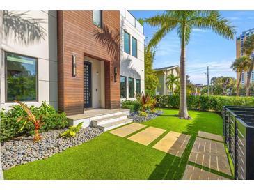 Modern home featuring an artificial turf lawn with stone walkways, lush landscaping, and a wood facade at 103 5Th N Ave, St Petersburg, FL 33701