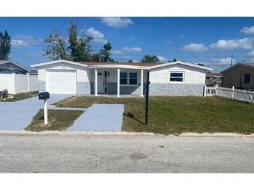 Charming single-story home featuring a light gray and white exterior with a well-manicured front yard at 4803 Guardian Ave, Holiday, FL 34690