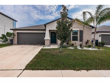 Single-story home with two-car garage and well-manicured lawn at 14906 Imperial Purple Ln, Wimauma, FL 33598