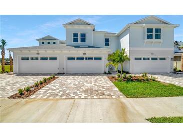 Three-car garage home with light-colored exterior and landscaped front yard at 31873 Anchor Point Dr, Wesley Chapel, FL 33545