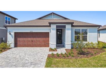 Charming single-story home featuring a brown garage door and well-manicured front yard at 6741 Michael Favor Way, Wesley Chapel, FL 33545