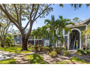 Two story building with gray siding, surrounded by lush landscaping and walkways at 2101 Fox Chase Blvd # 106, Palm Harbor, FL 34683
