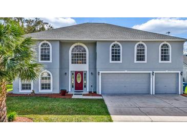 Two-story house with gray siding, red door, and two-car garage at 8378 Gibralter St, Spring Hill, FL 34608