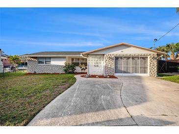 Charming single-story home featuring stone accents, a screened garage, and a well-maintained front yard at 5346 Quist Dr, Port Richey, FL 34668