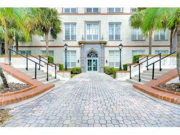 Grand building entrance with brick walkway, stairs, and lush landscaping at 701 Mirror Lake N Dr # 309, St Petersburg, FL 33701