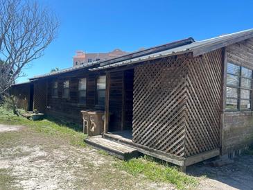 Rustic one-story home featuring wood siding, a metal roof, and a charming lattice-covered porch at 113 Boca Ciega Dr, Madeira Beach, FL 33708