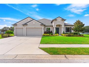 Two-story house with three-car garage, manicured lawn, and mature trees at 913 Buckhurst Dr, Spring Hill, FL 34609