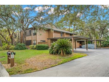 Exterior view of home with multi-car carport, lush landscaping and mature trees at 104 Cypress Pond Rd, Palm Harbor, FL 34683