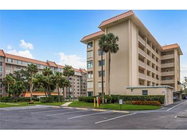 Exterior view of a mid-rise condominium building with palm trees and landscaping at 620 Edgewater Dr # 304, Dunedin, FL 34698